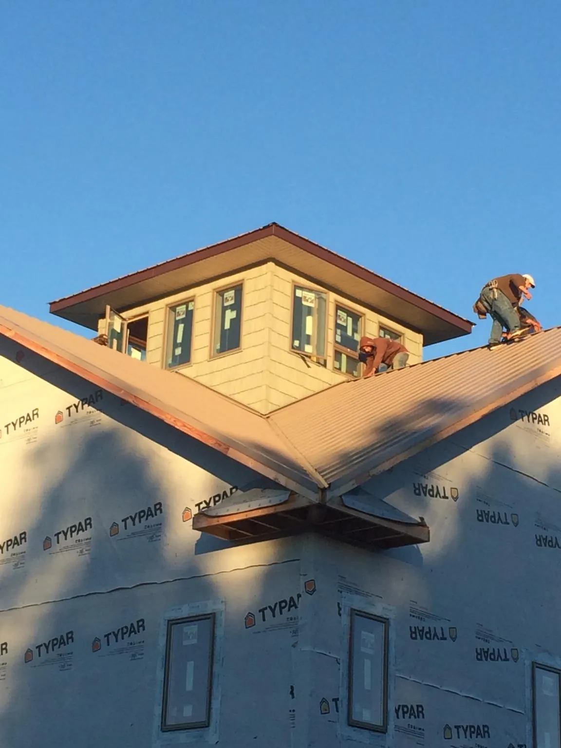 Roofers working around a rooftop cupola on a new metal roof at sunset — Roof Waterproofing in Fenton by Roofing Brothers